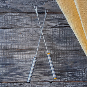 Two fondue forks on a rustic wooden background.